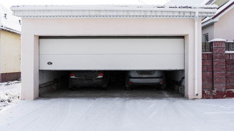 Garage with door partially raised on a snowy day