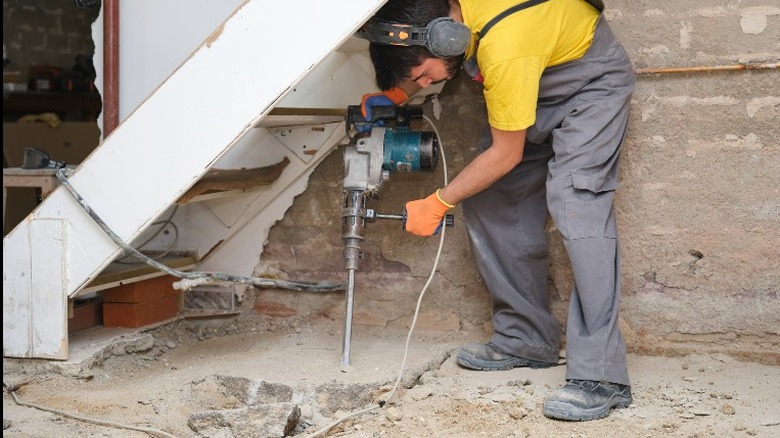 A man uses a jackhammer to break a concrete floor