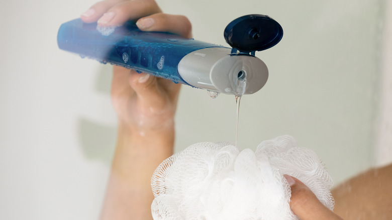 holding shower gel and loofa