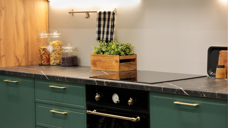 Light and bright lit kitchen with laminate countertop and green cabinets