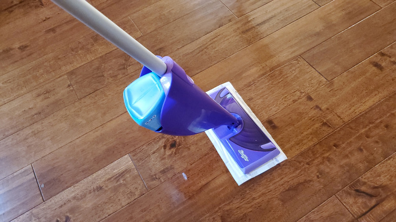 A Swiffer WetJet mop being used on a hardwood floor