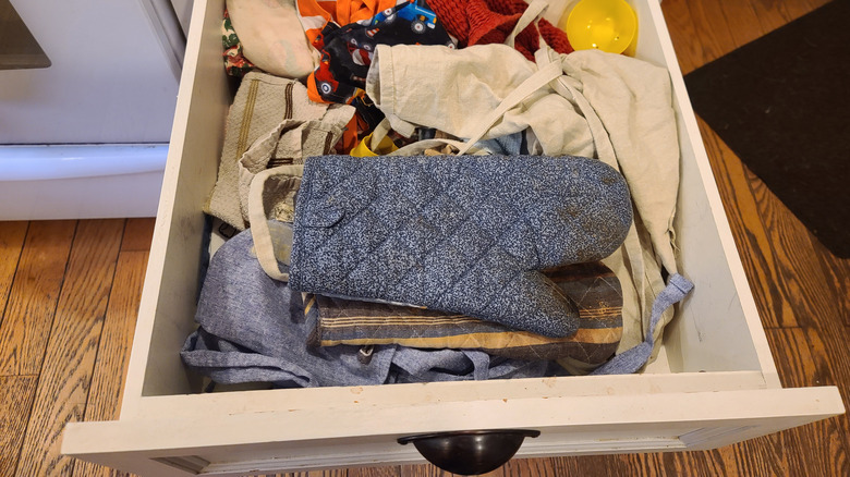 messy drawer with oven mitts