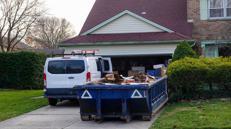 Dumpster full of trash in front of residential home