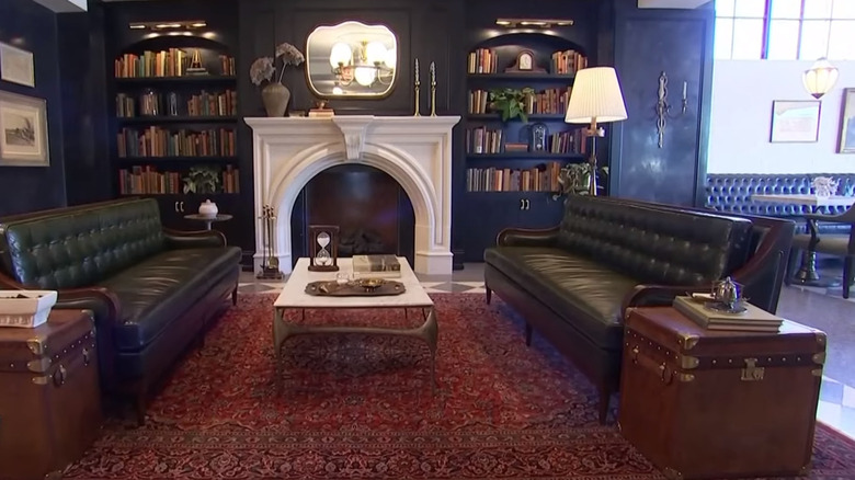 Hotel 1928's café area with dark walls, white fireplace, and Persian rug