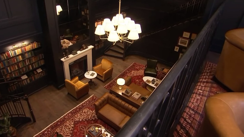 The Hotel 1928 library with dark walls, red Persian rugs, and leather furniture