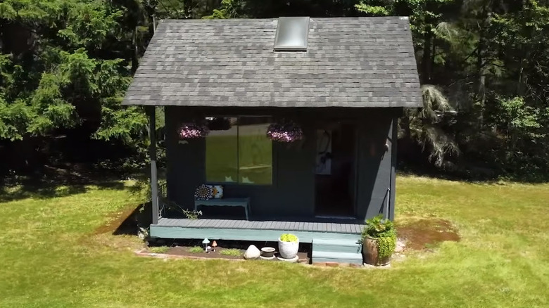 Gray potting shed with hanging baskets and porch