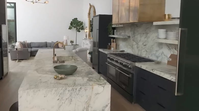 Kitchen with marble island, counters, backsplash, and black cabinets