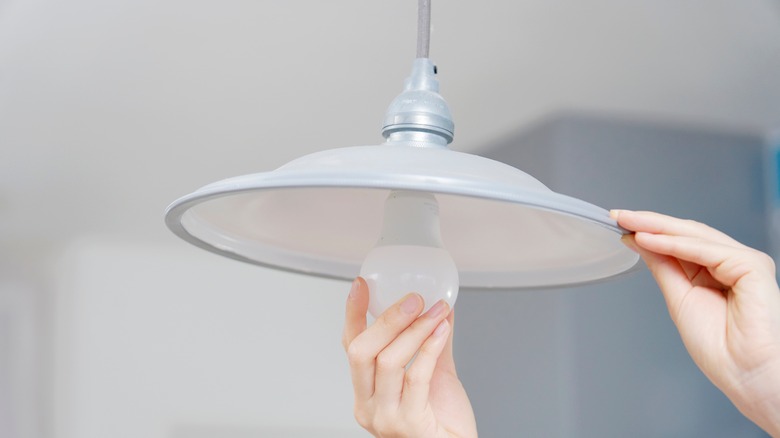 Woman changing the bulb in a pendant light