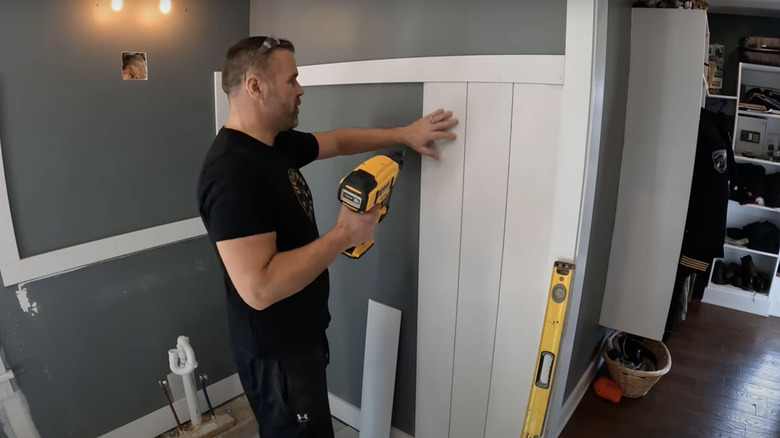 man installing shiplap on bathroom wall 