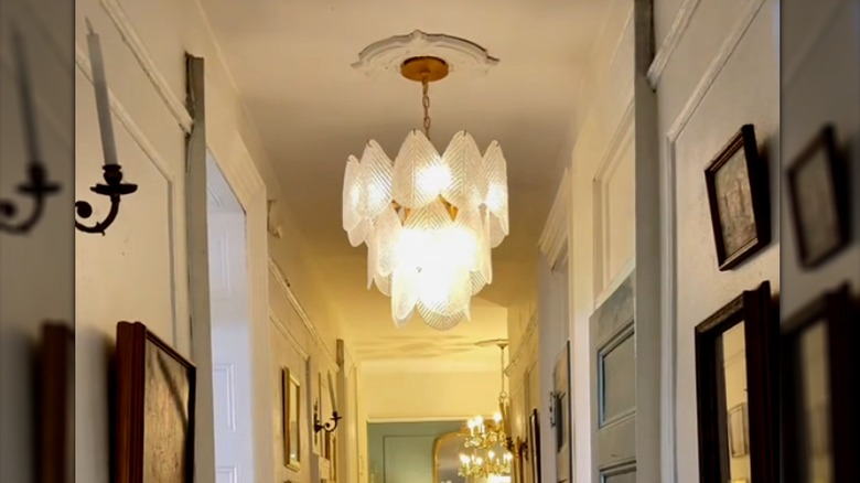 Decorative light fixture hanging in white hallway in home