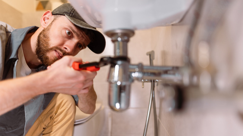 man repairing plumbing on sink