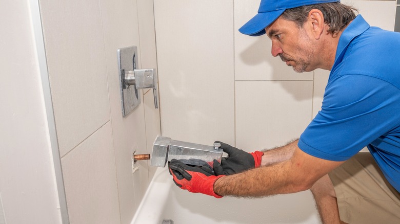 Man removes tub faucet