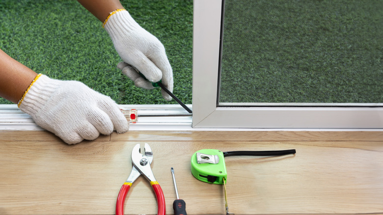 A worker repairing the bottom of a sliding glass door