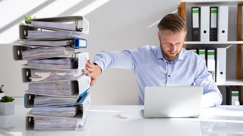 man pushing away stack of papers