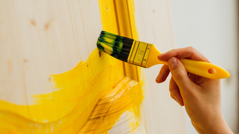 A person painting wooden door