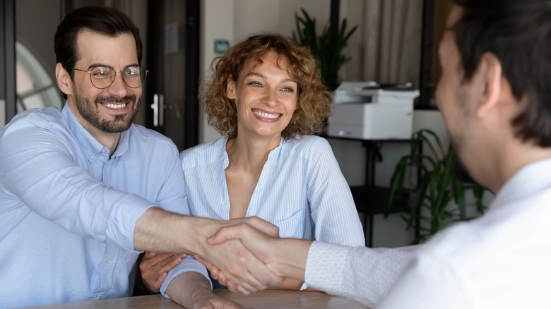 Couple shakes hands with businessman