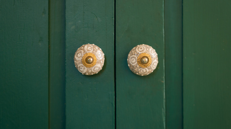 Textured brass knobs on green doors