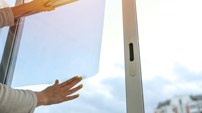 person adding film to window