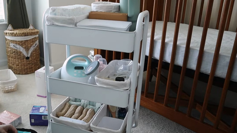 The white RASKOG cart with baby items in nursery