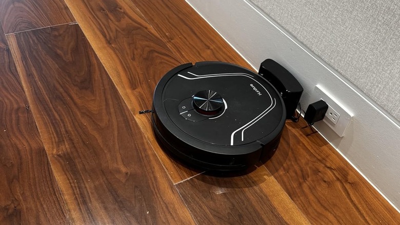 black robot vacuum charging on hardwood