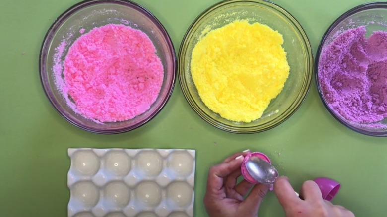 Person packing bath bomb powder into a plastic Easter egg as a mold