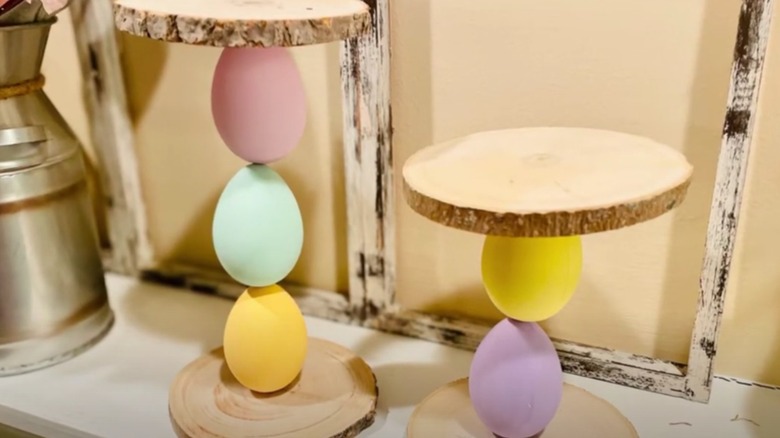 Plastic eggs stacked between thin pieces of wood to form candle holders