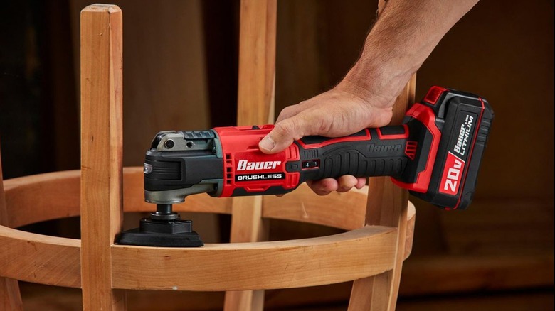 A person using a multi-tool on furniture