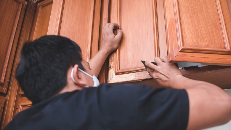 A man repairing a kitchen cabinet