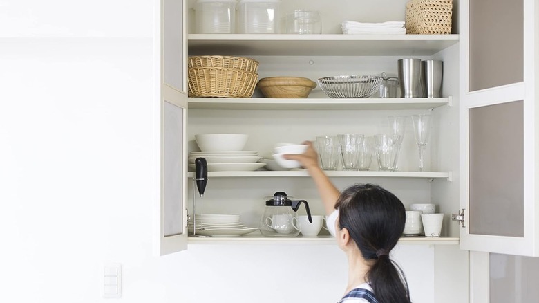 A person reaching into a kitchen cabinet