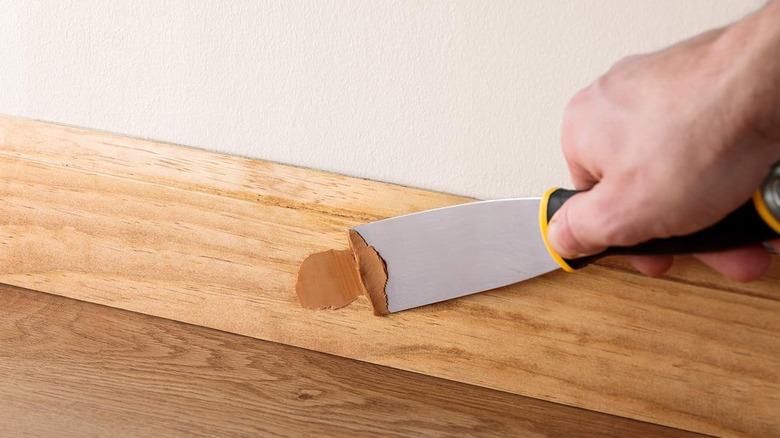 A person using Minwax putty to repair wood