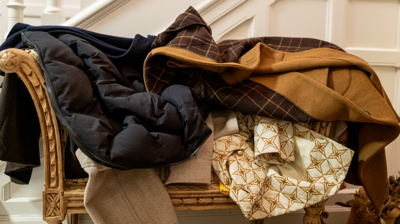 Jackets piled on ornate chaise style bench