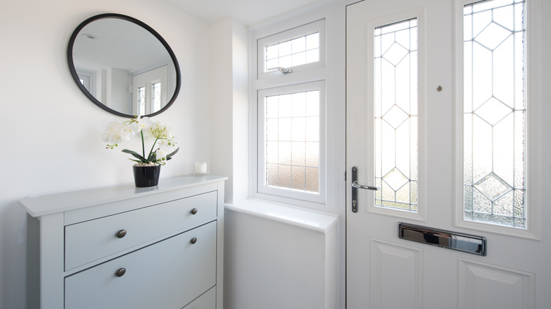 All white entryway with grey cabinet and mirror