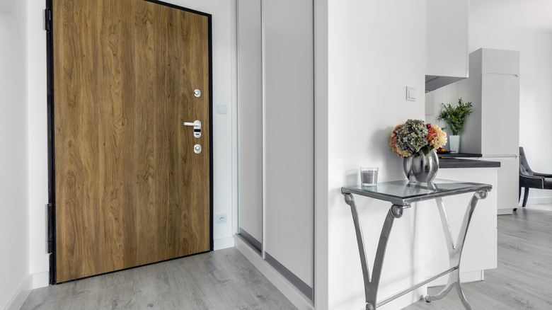 Simple silver and glass table beside a large wood door