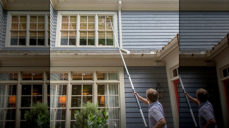 A man cleans windows with an extension duster