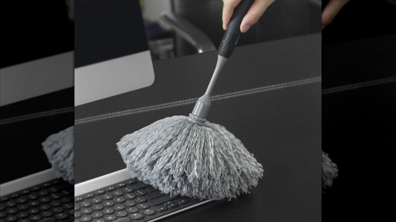 A grey microfiber duster is used to clean a keyboard