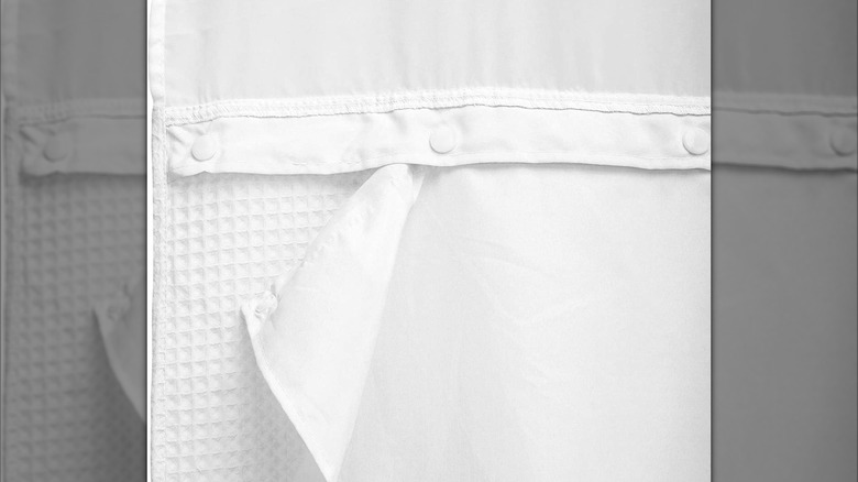 Three snaps on a white honeycomb textured shower curtain liner are shown in detail