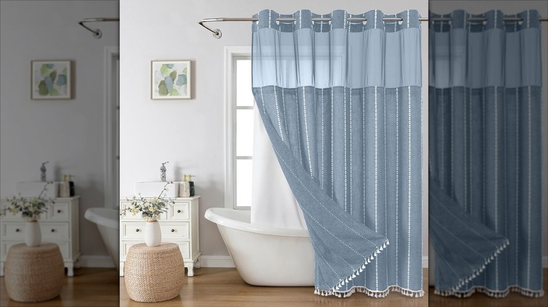 A thick blue striped boho style shower curtain is folded back to show a white liner