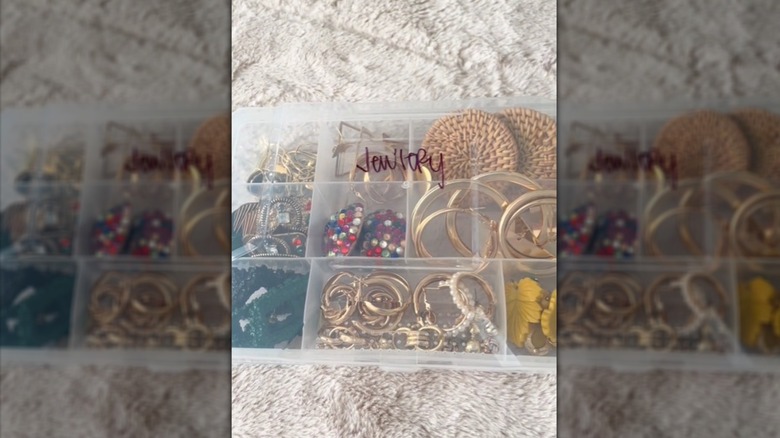 Plastic hardware storage case with jewelry inside, the word jewelry in black marker on front