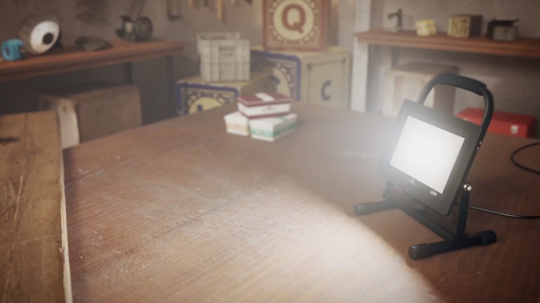 A bright worklight is shown on a wooden table in a garage