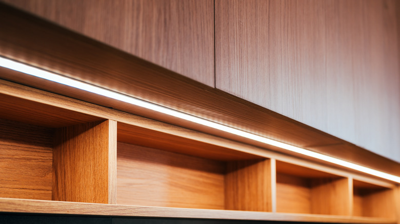 A bright strip of lights is mounted under wood veneer cabinets