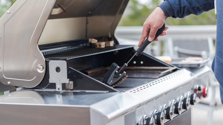 person cleaning outdoor grill