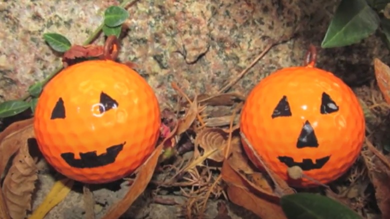 orange golf balls decorated with jack-o'-lantern faces