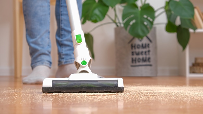 Man in jeans cleaning floor with cordless vacuum cleaner 