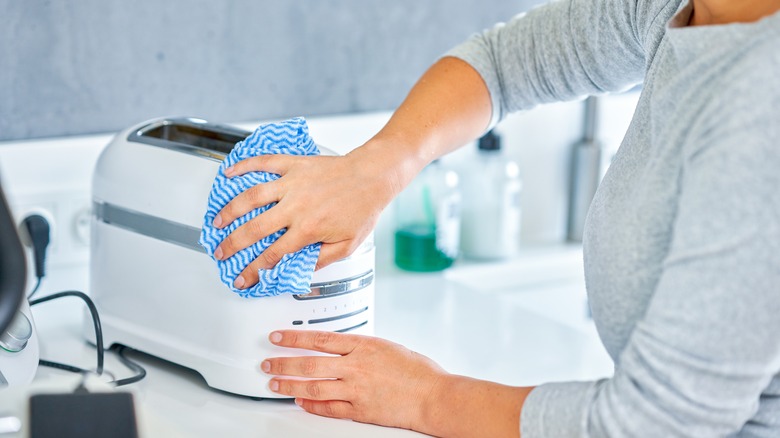 Woman cleaning grill or toaster machine in the kitchen