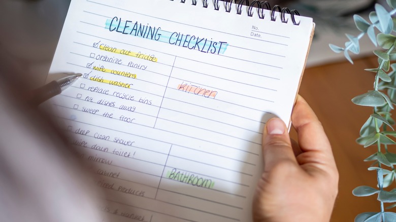 Person holding a handwritten cleaning checklist