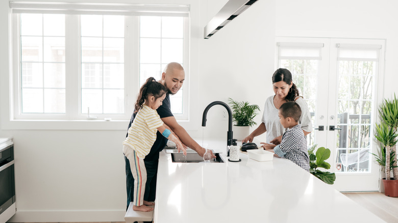 Family with two kids around kitchen island doing chores