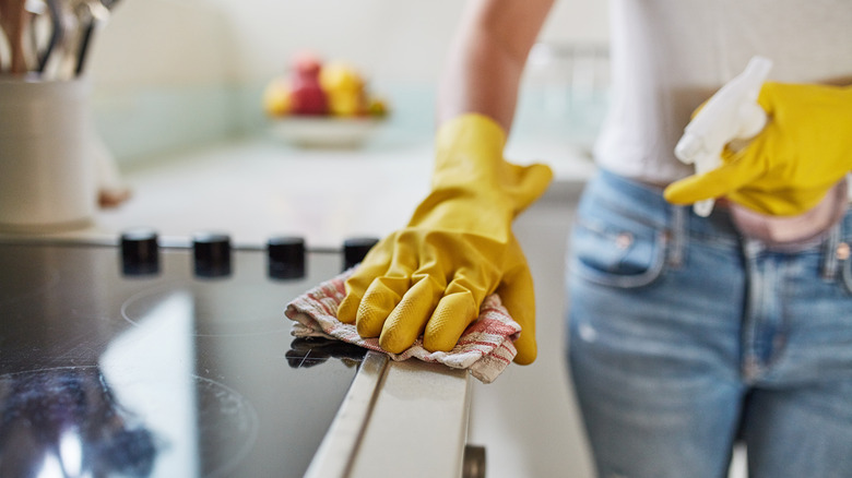 Woman wearing yellow gloves wiping down counntertops