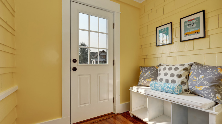 yellow foyer with a bench