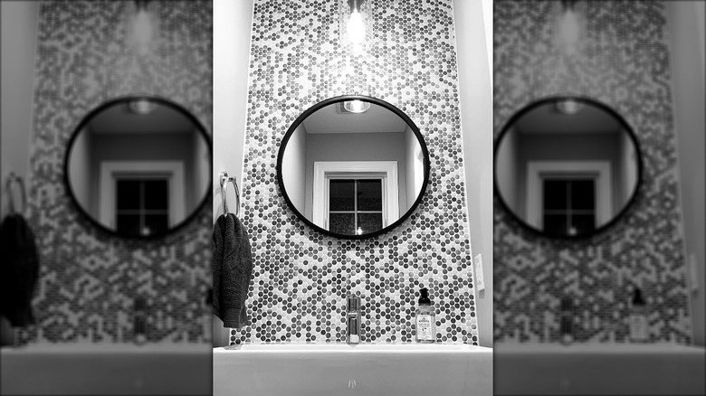 Black, white, and gray accent backsplash above a bathroom sink made from penny tiles