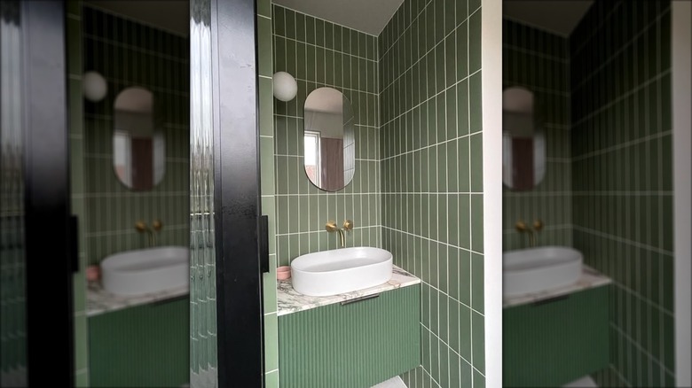 Small bathroom vanity area with green tiles stacked vertically